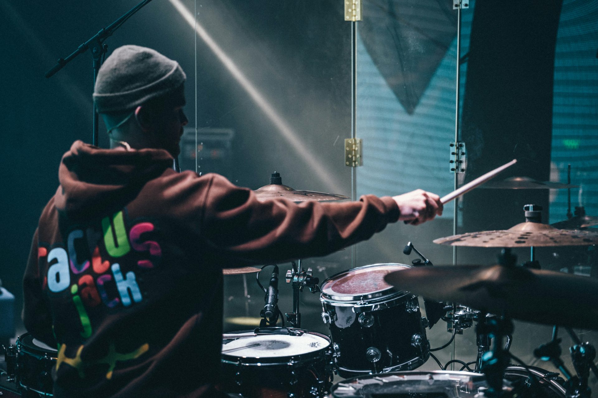 a man with a hoodie on playing drums